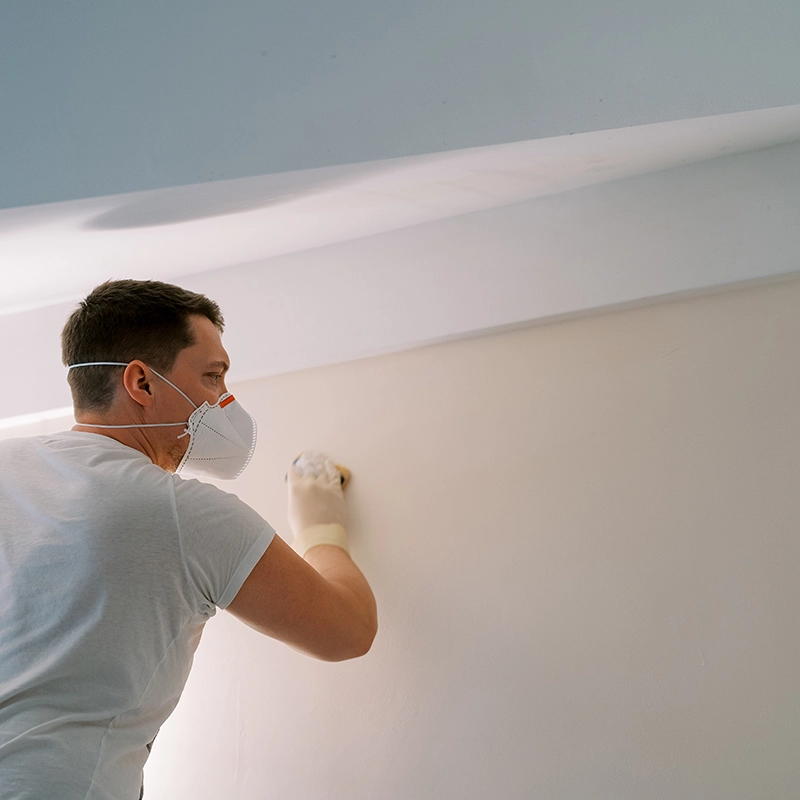 Pintor alisando pared para después pintar.