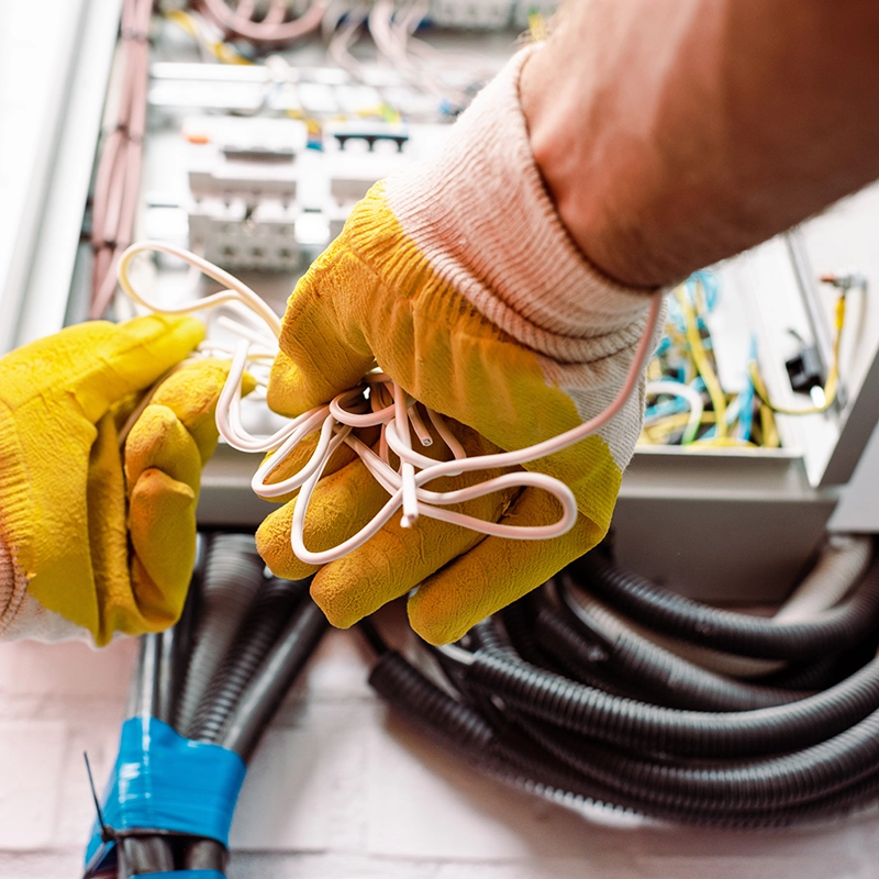 Electricista trabajando con cables en un cuadro de luz.