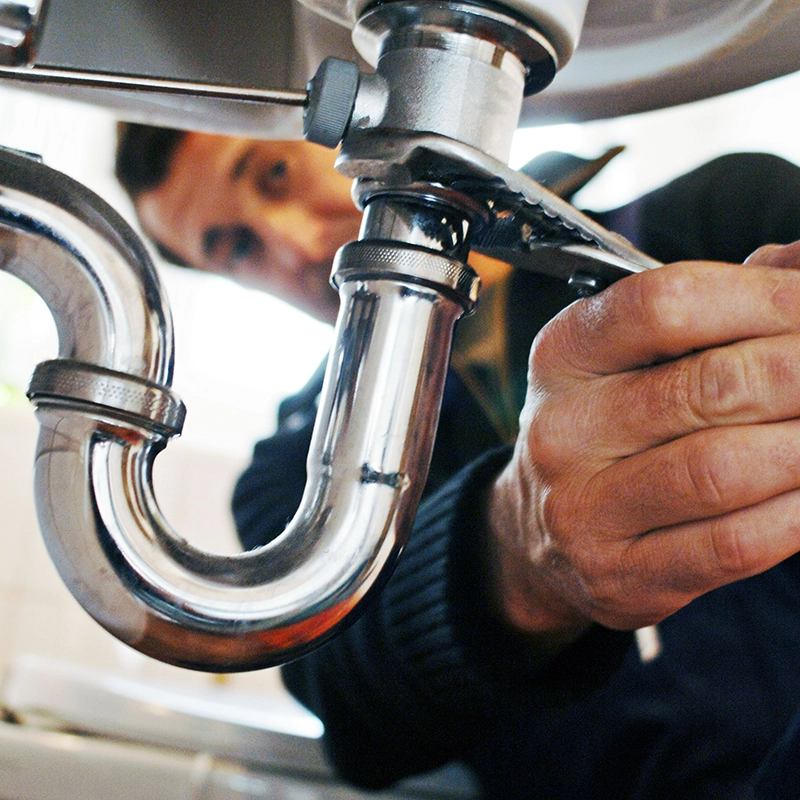 Fontanero con llave arreglando un fregadero.